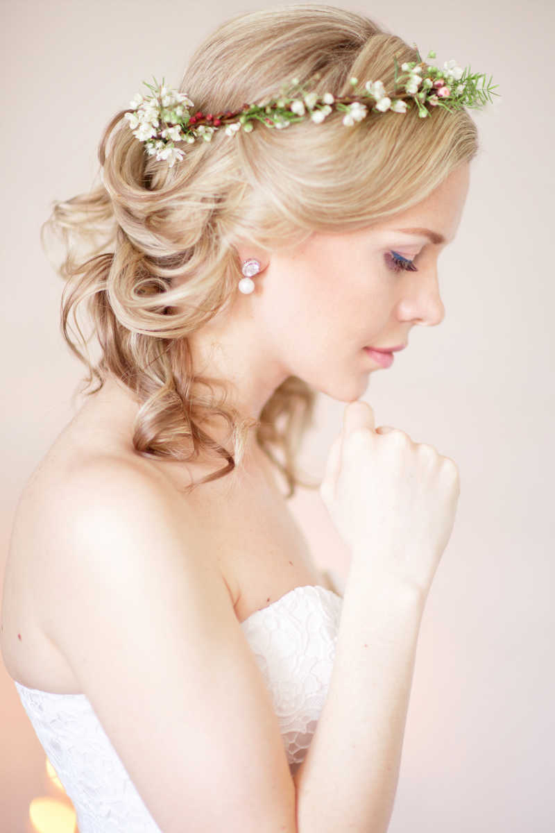 浅色背景下发型上戴着花朵的美丽新娘