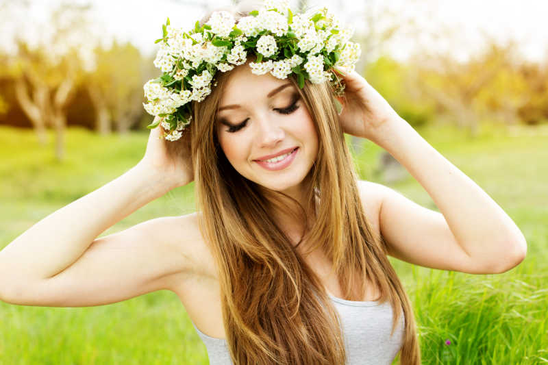 草地上戴着白色花朵的年轻女子