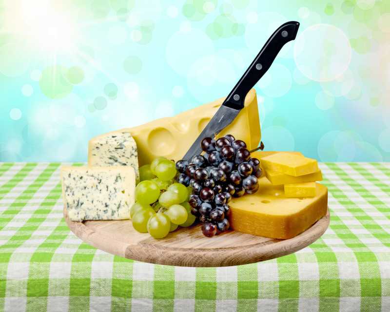 绿色桌布上的起司奶酪葡萄与刀具