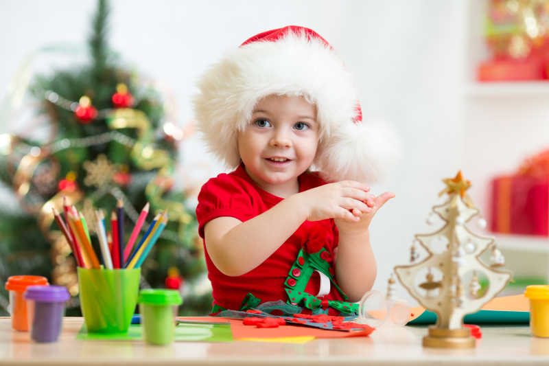 带着圣诞帽的小女孩开心地制作小圣诞树