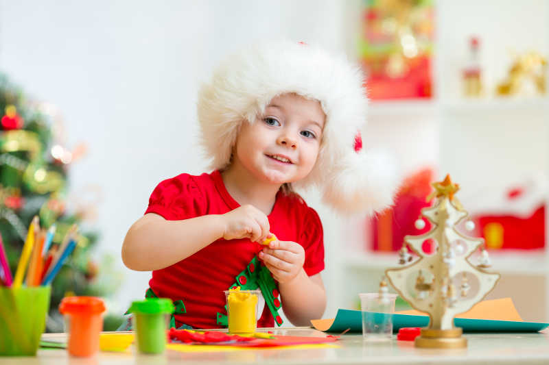 带着帽子的小女孩开心的制作圣诞树