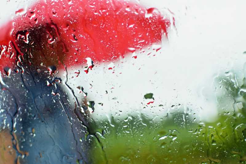 下雨天站在窗外打着红色雨伞的模糊男人