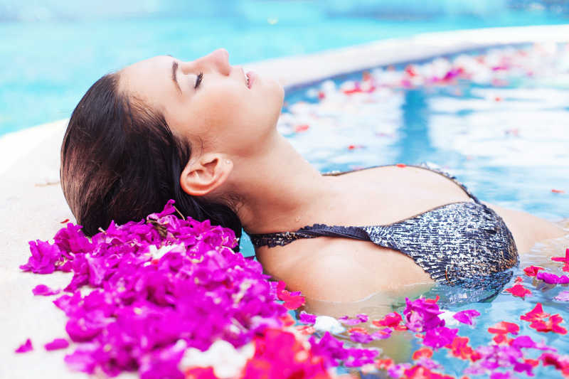 美女躺在满是花瓣的温泉里泡澡