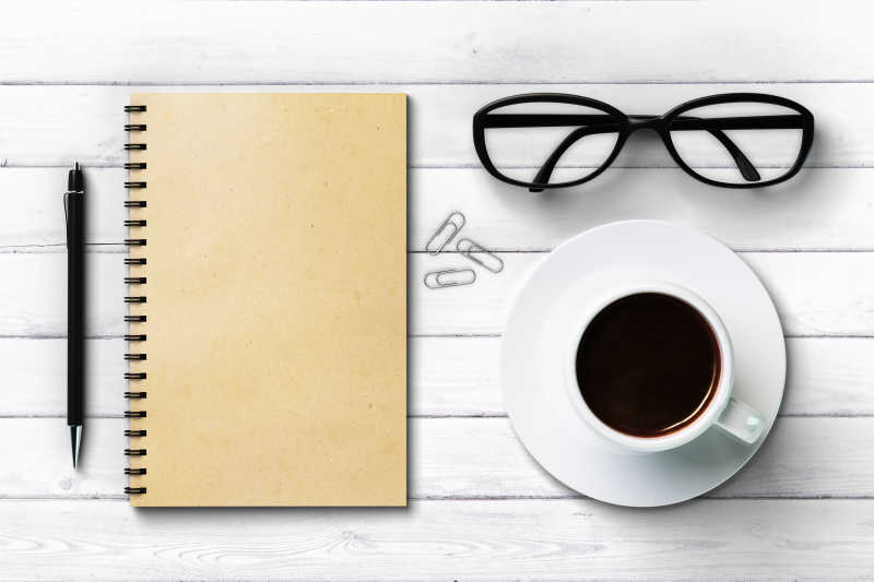 白色木制背景上笔记本和咖啡眼镜