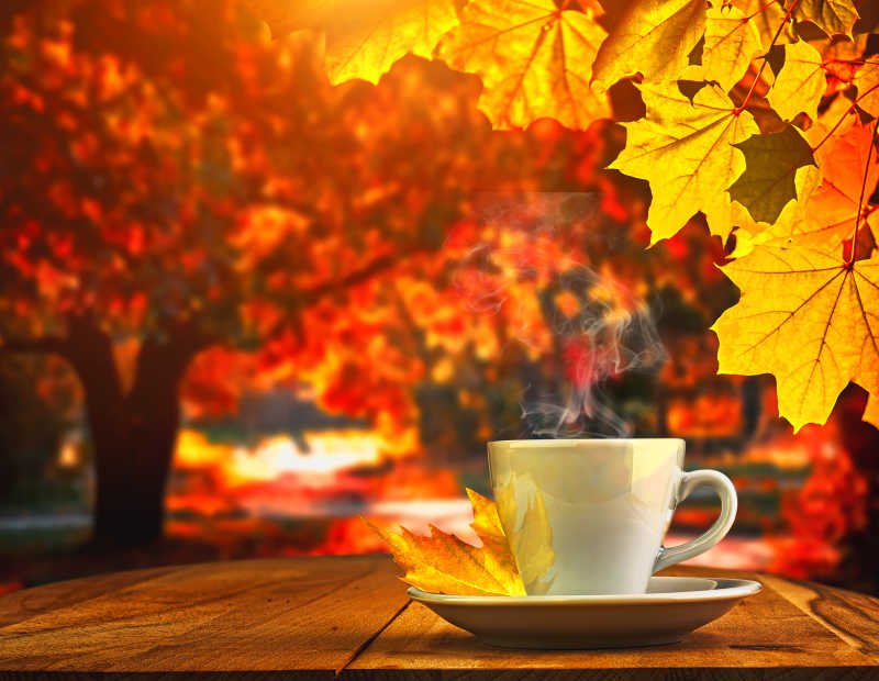 秋天背景下木质桌上的一杯热咖啡