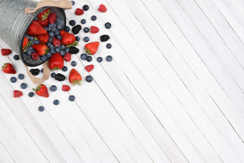 白色厨房餐桌上的草莓蓝莓和黑莓等水果特写
