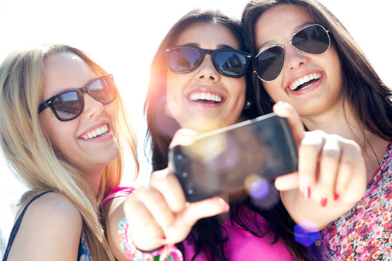三个戴墨镜女性朋友用手机自拍