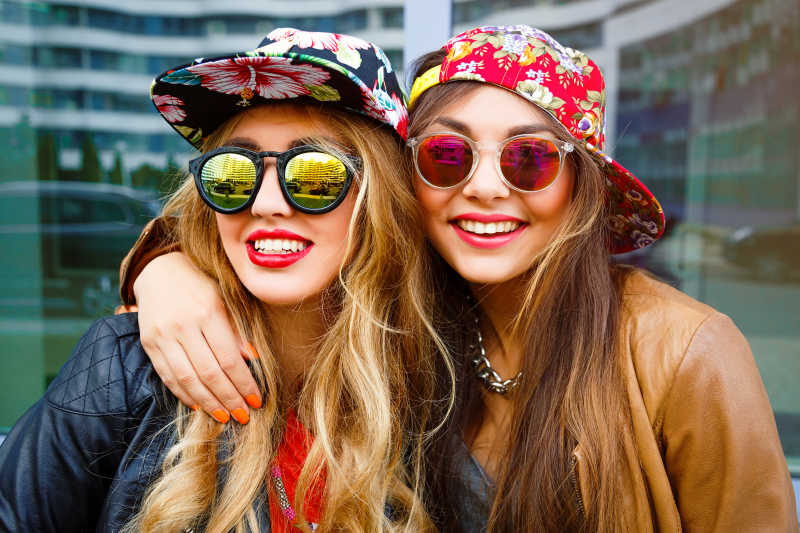 戴着帽子和眼镜的两个年轻时尚女子