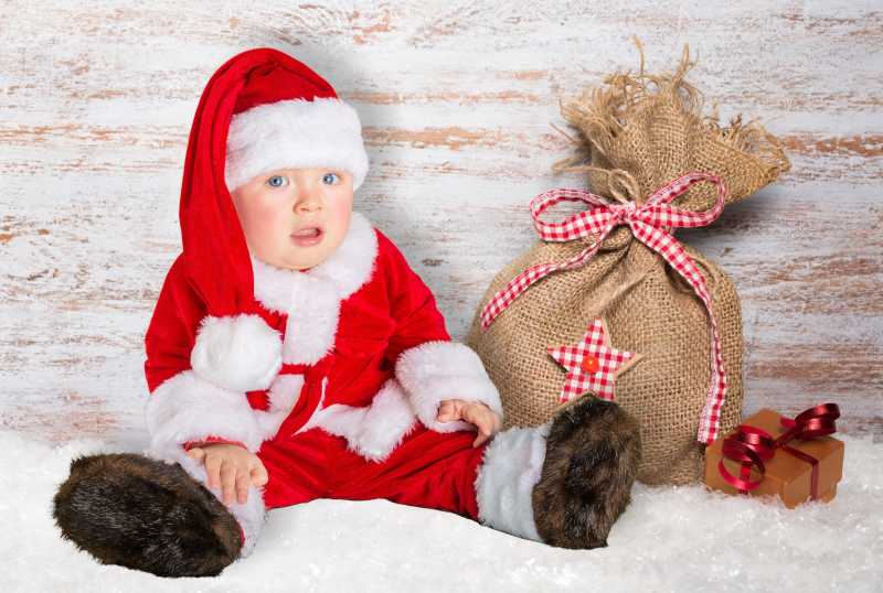 穿着圣诞服装的宝宝和装礼物的那袋