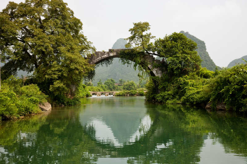 绿色群山中河流上的拱桥
