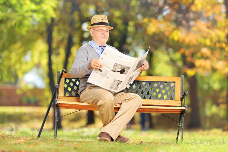 公园里坐在板凳上看报纸的老人