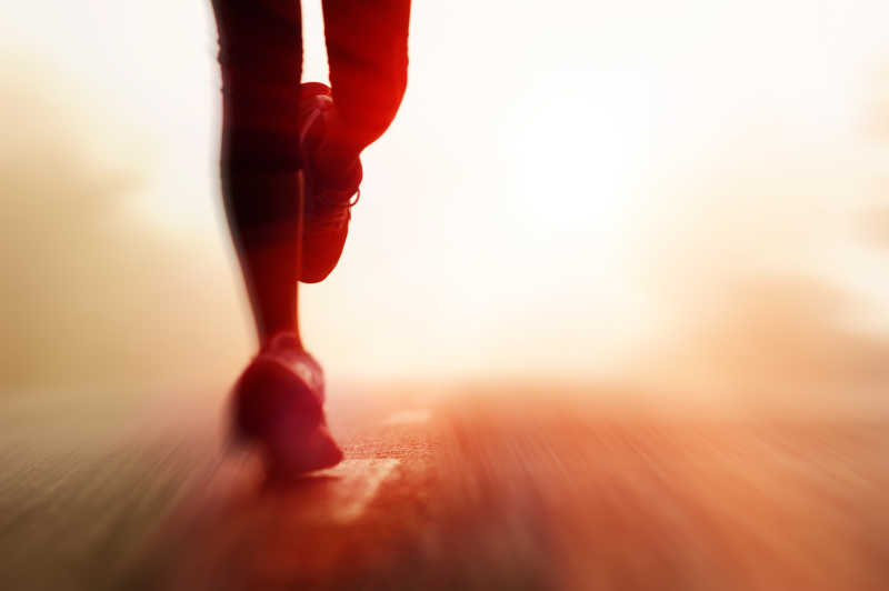 阳光下跑步运动员脚和腿部模糊镜头特写