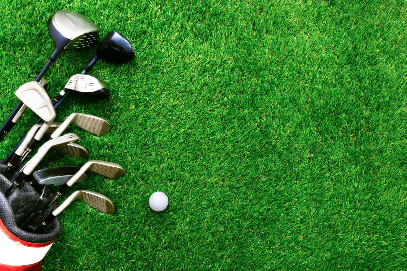 绿色草地上的高尔夫球杆与高尔夫球