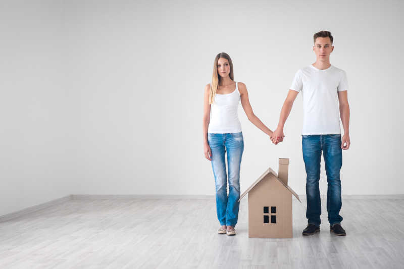 年轻夫妇与纸板房屋模型