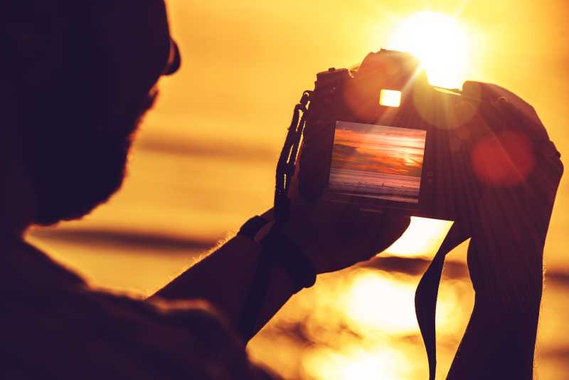 男人用数码相机拍摄晚霞景观