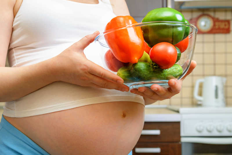 一位孕妇端着健康食品