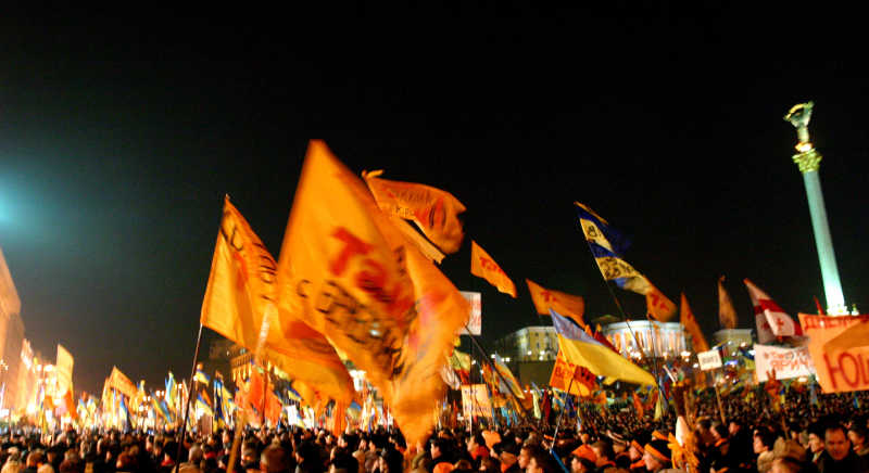 夜空下举着橙色旗子的人们