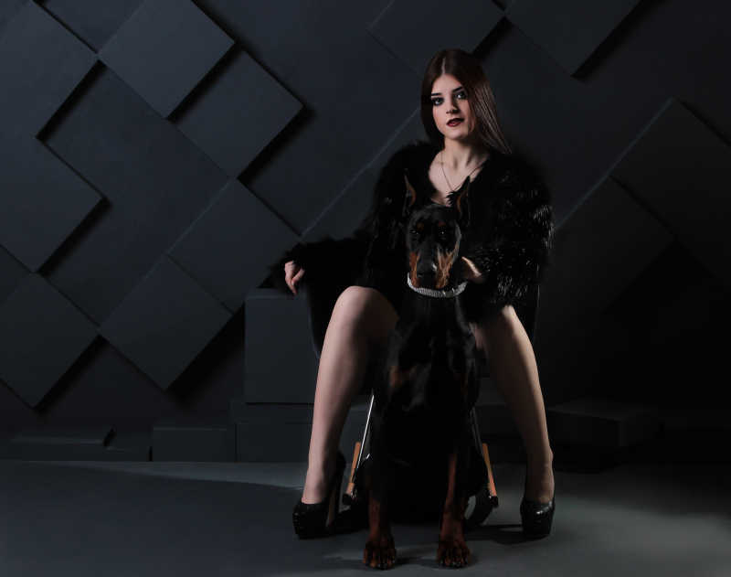 美丽时尚的女人坐在黑色杜宾犬身边