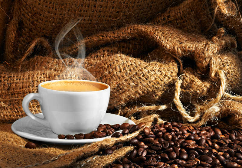 麻袋背景上的热咖啡和咖啡豆