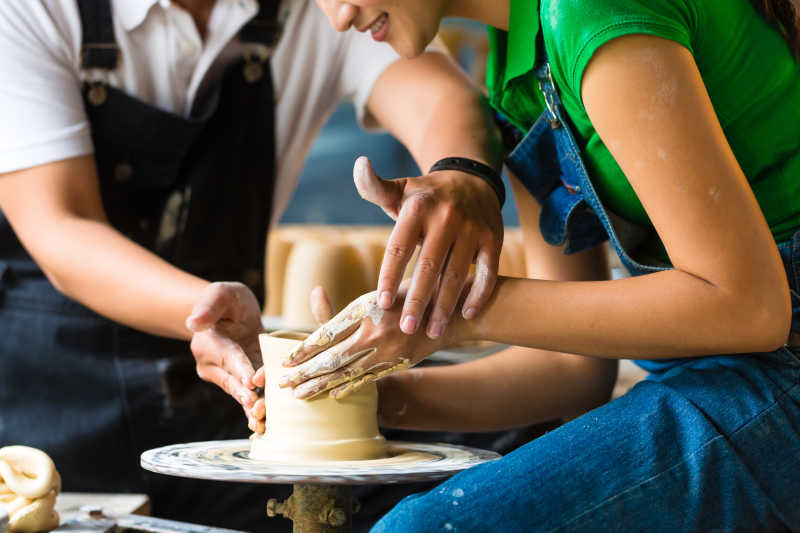 波特师傅帮助女陶工在陶工轮子上创造了一个碗