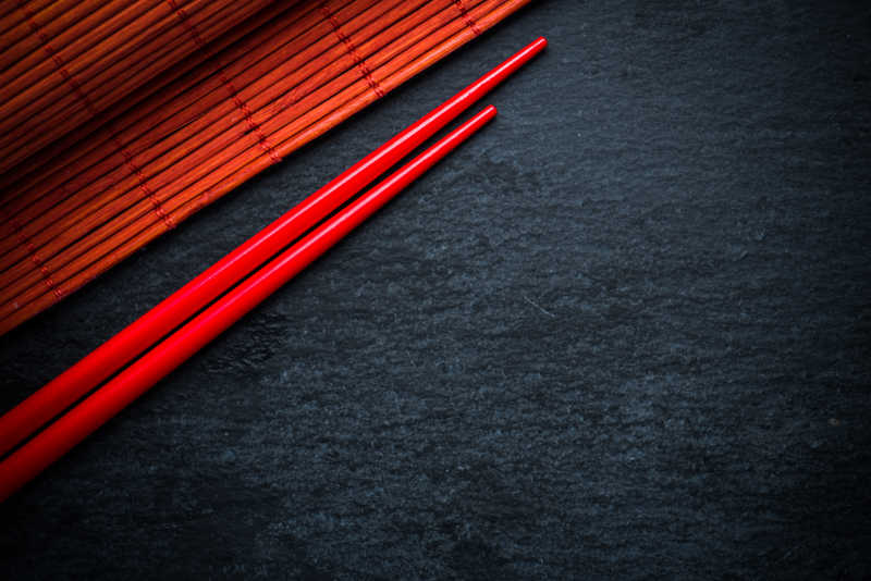 日本红筷子和竹凉席在黑色石板上