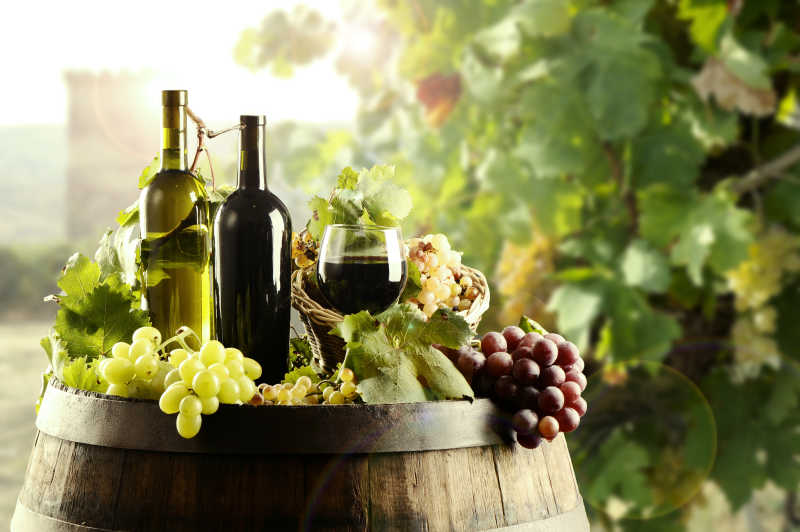 木桶上面的新鲜葡萄和红酒杯子以及瓶子特写