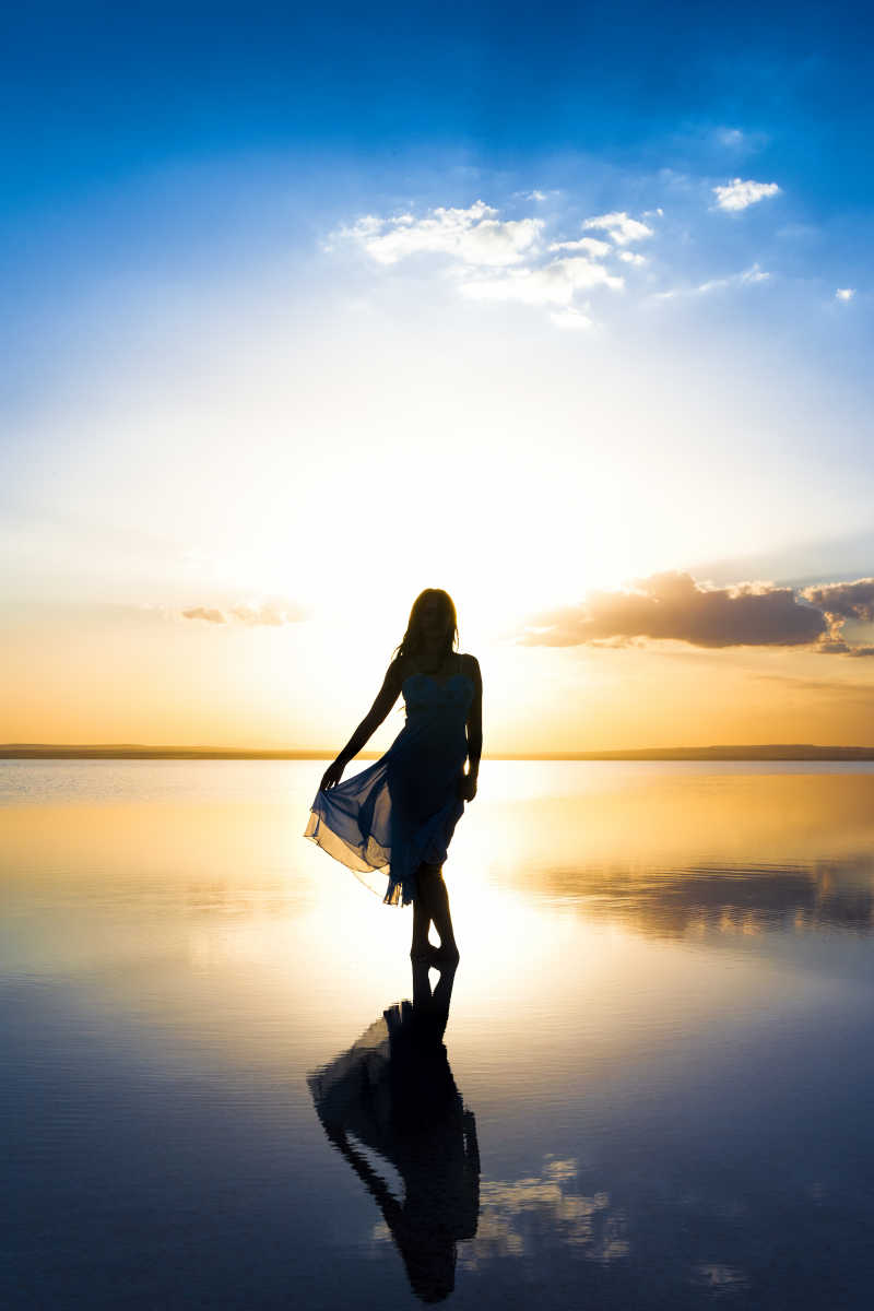 日落时分站在盐湖上的女人