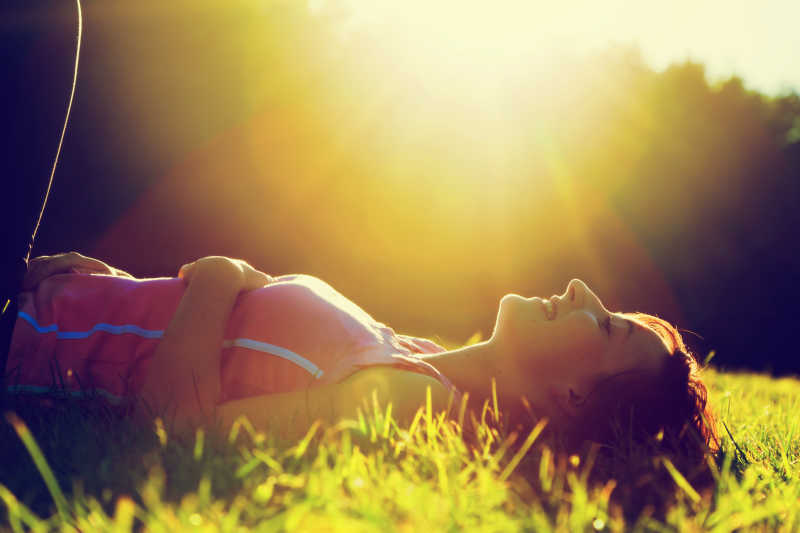 夏日夕阳下躺在草地上的年轻美女