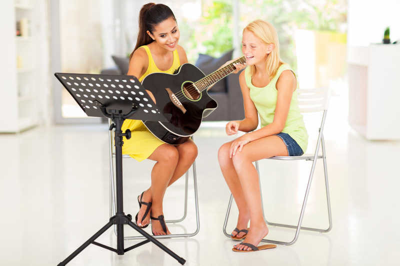 年轻漂亮的小女孩在家里上吉他课