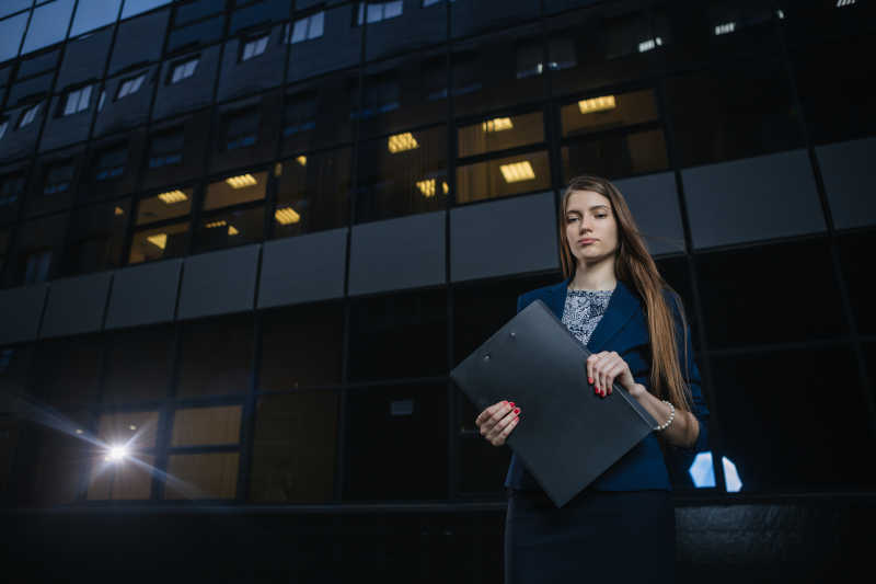 成功的年轻女商人站在背景建筑前面