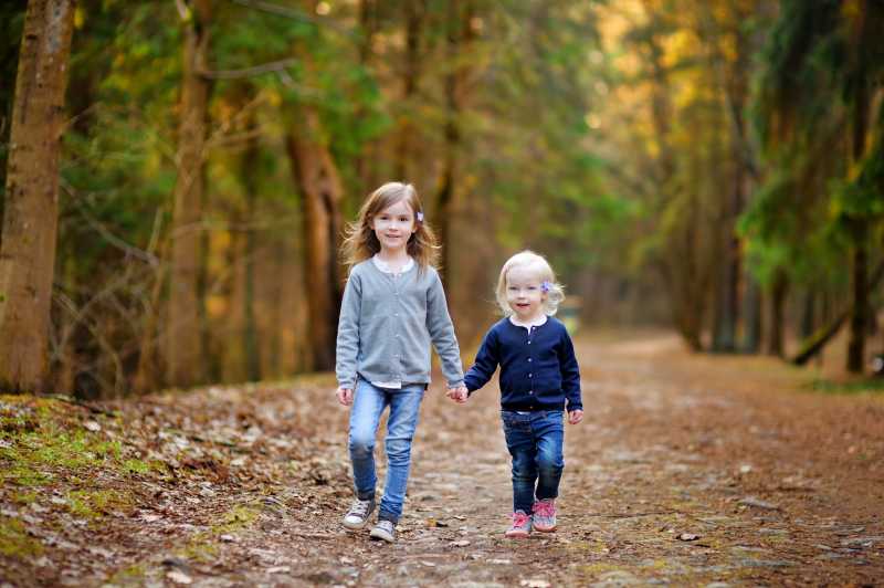 走在乡间森林道路上的两个小女孩
