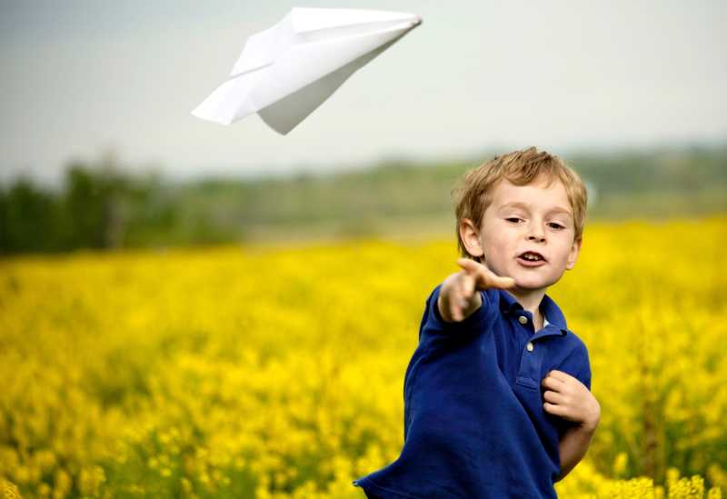 户外玩纸飞机的小男孩