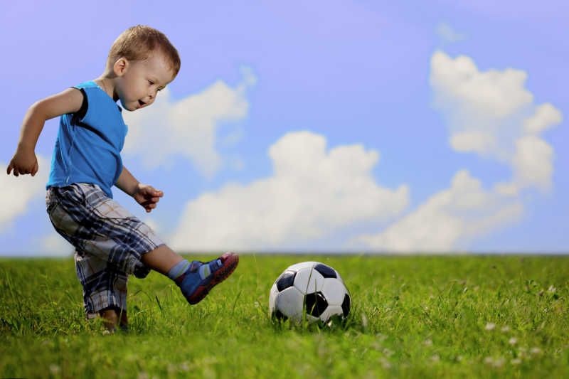 草地上踢足球的小男孩