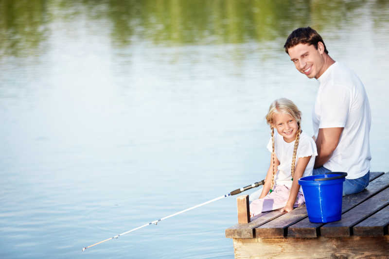 湖边码头钓鱼的快乐父女