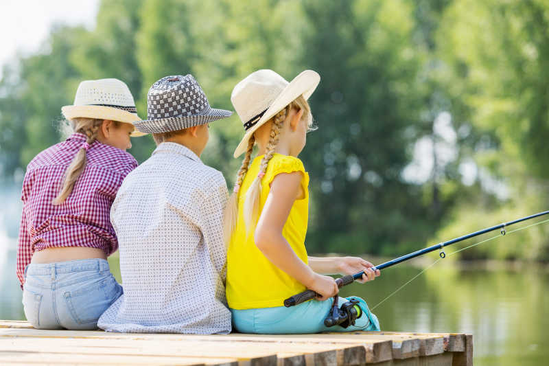 坐在码头边钓鱼的三个孩子