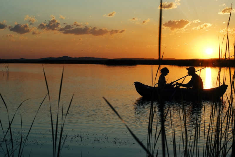 日落黄昏河流船只里钓鱼的两个人