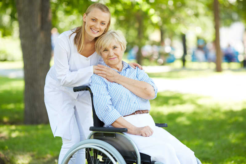 公园里的漂亮护士与轮椅上的老年人
