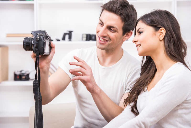 年轻夫妇或情侣看着相机里的照片