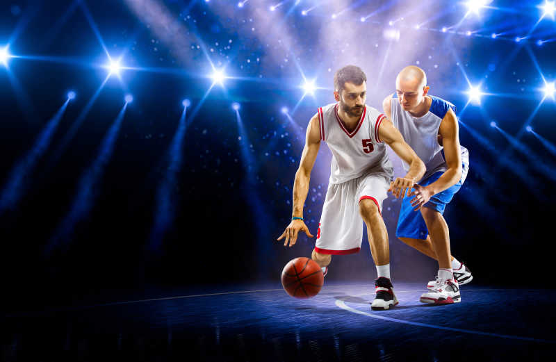 两个篮球运动员在灯光场上表演