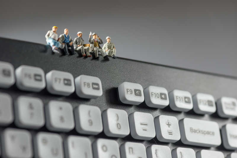 坐在电脑键盘上的小型工人
