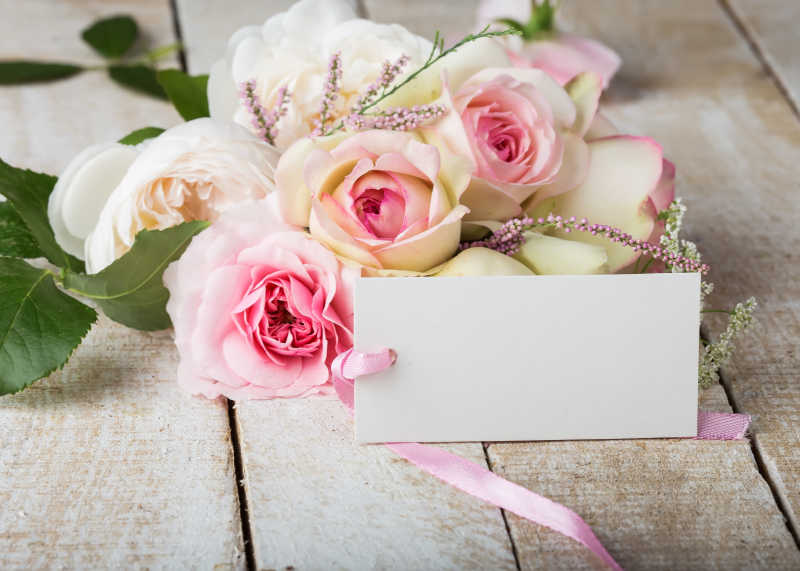 木制背景下的粉红色玫瑰鲜花和空白明信片