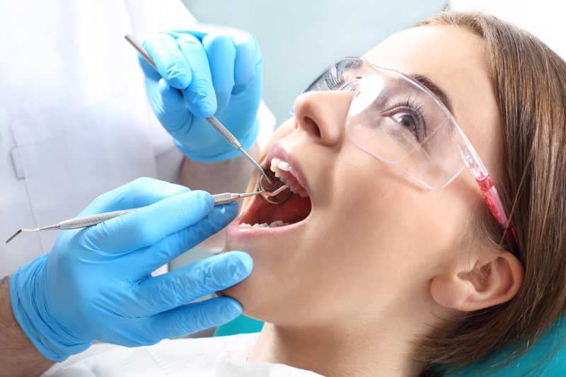 女人在接受牙医拿着检查工具进行牙科检查