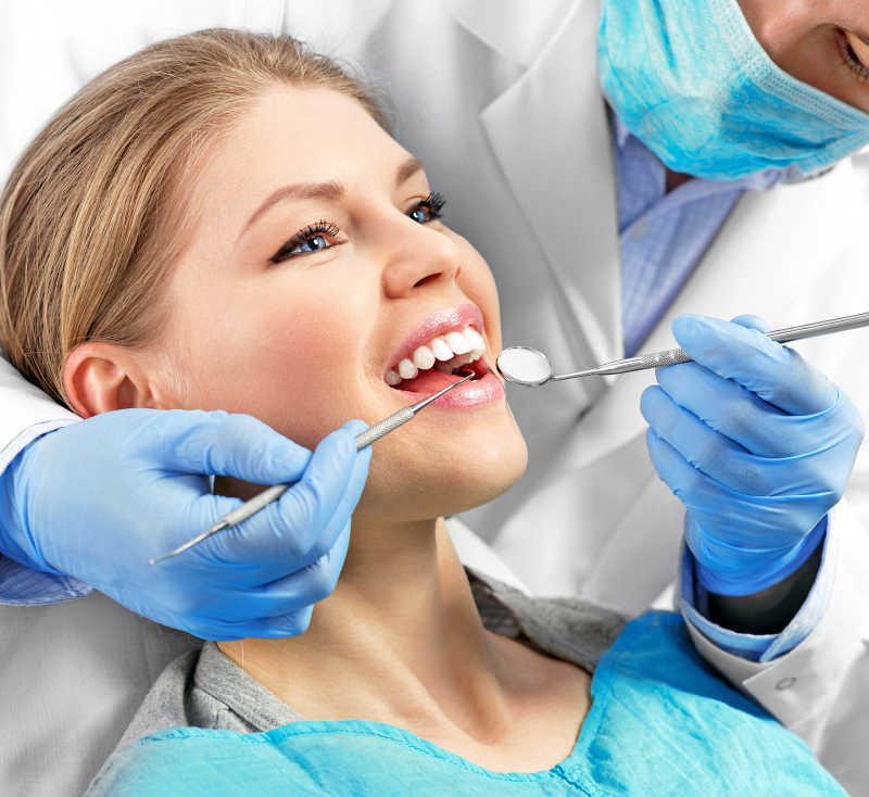 牙医拿着工具给女人做牙科检查