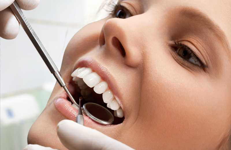 牙医拿着工具在给女人做牙科检查