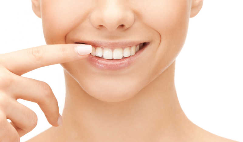 白色背景下女人伸出手指指着洁白健康的牙齿