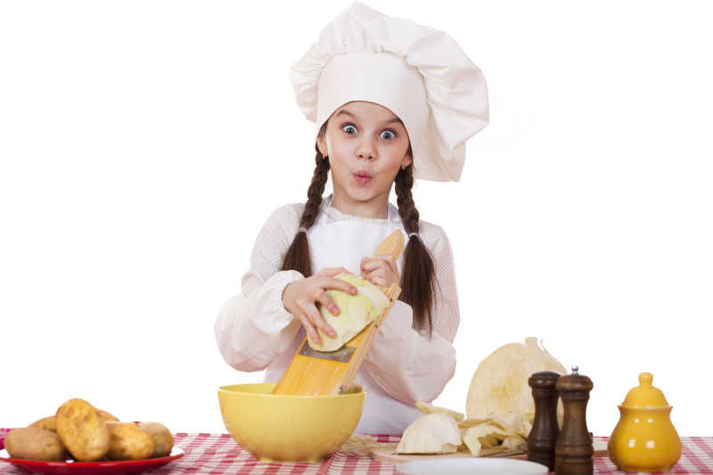 戴着厨师帽的小女孩在削卷心菜