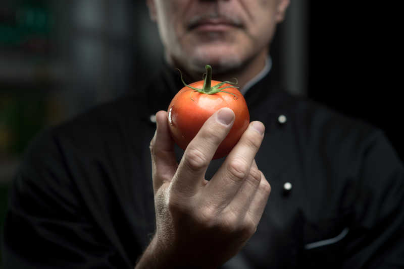 手拿着番茄的厨师