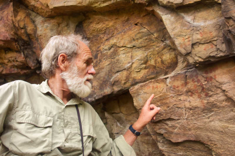 老考古学家指着岩石上的古老壁画