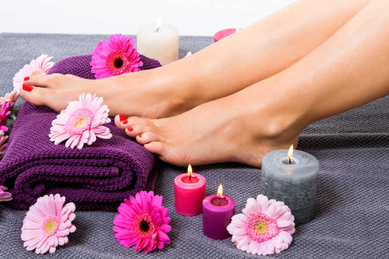 女性的双脚放在毯子上边上放着蜡烛与花朵