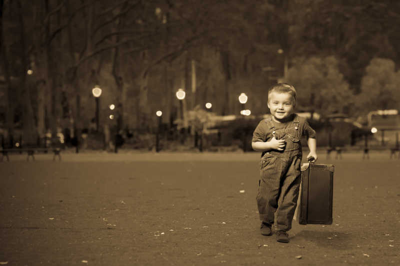 拿着行李箱微笑着的外国小男孩